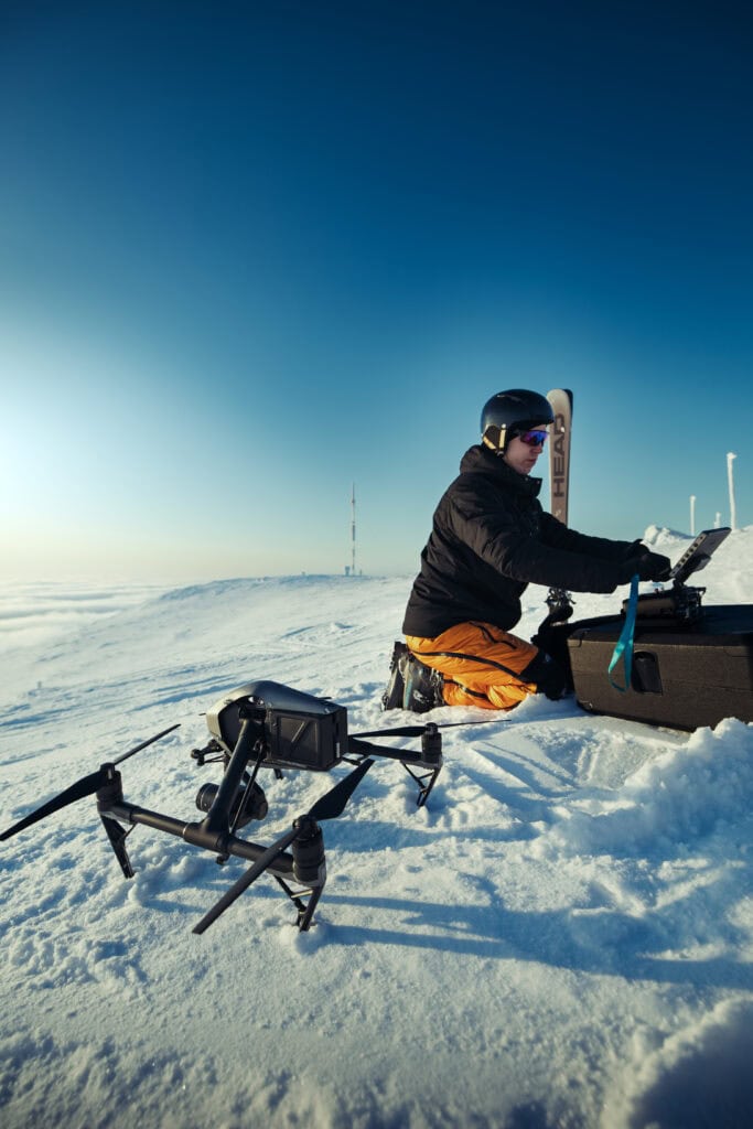 DJI Inspire 2 -drone lumella, lentäjä työskentelee kalustolaukun ääressä tunturilla Ylläksellä