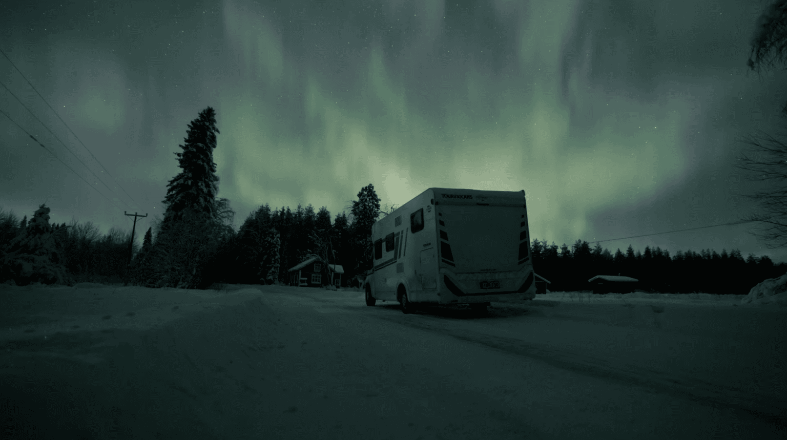 Revontulet Touring Carsin matkailuauton yllä lumisella tiellä Torniossa