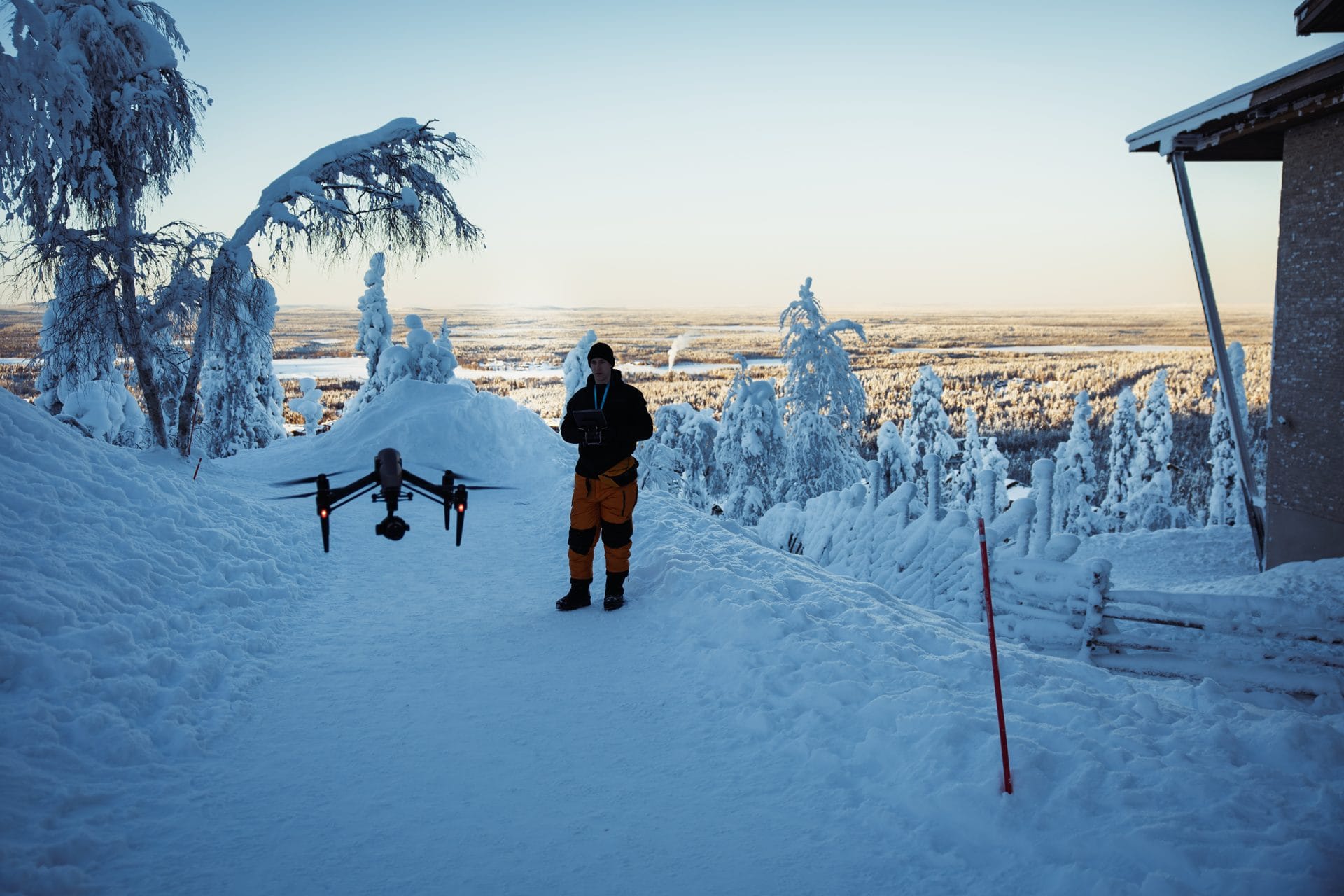 Fraymfulin dronelentäjä lumisella uralla, edessä maassa DJI Inspire 2 ja ympärillä huurteinen metsä Levillä