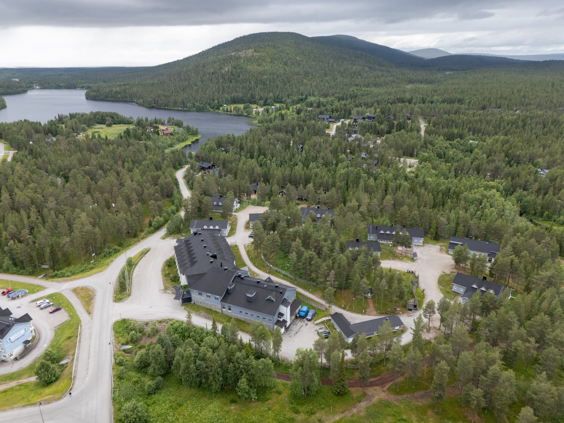 Hotel K5 Levi ja sen lomamökit mäntymetsässä, takana järvi ja tuntureita, Levi
