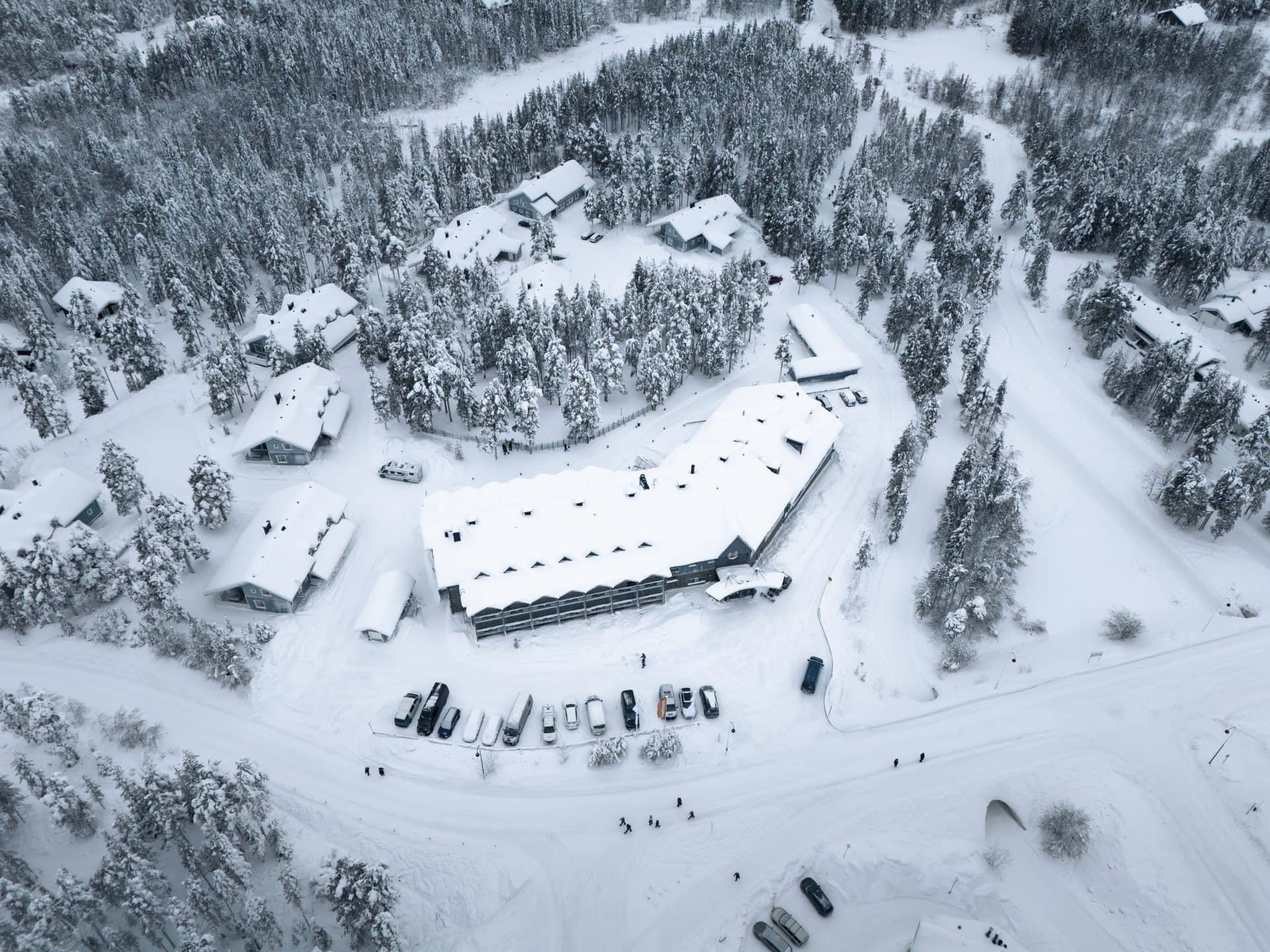 Suoraan ylhäältä kuvattu Hotel K5 Levi ja sen mökit lumisten mäntyjen keskellä Levin kylässä