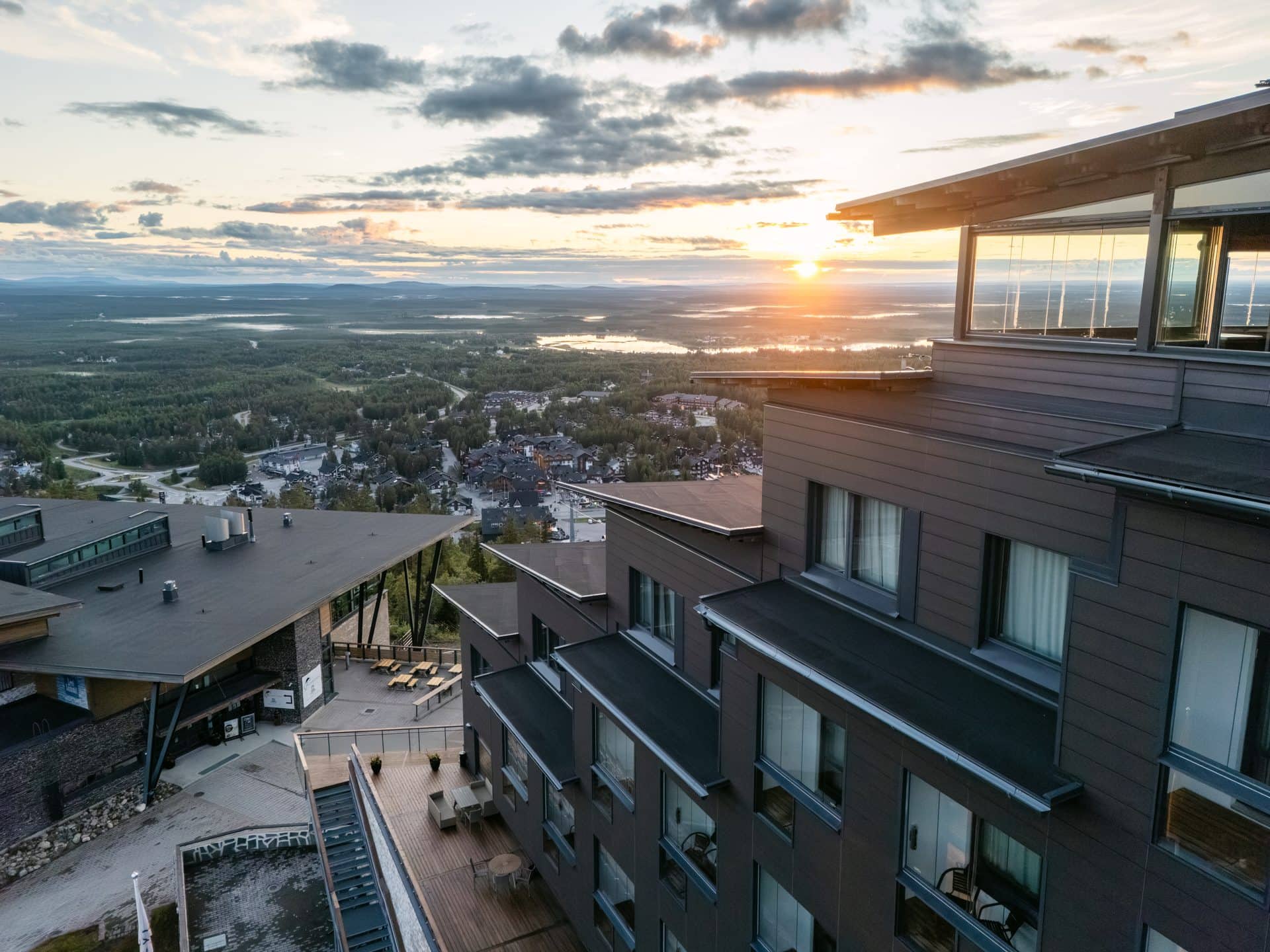 Keskiyön aurinko matalalla horisontissa Hotel Levi Panoraman ja sen kattoterassin takana Levillä