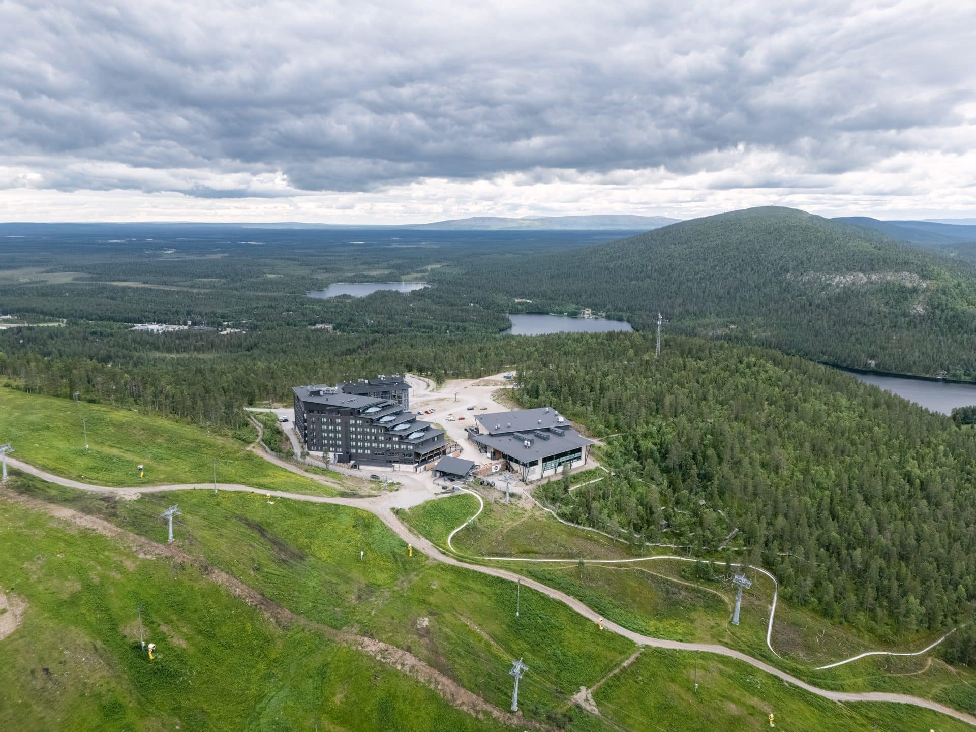 Hotel Levi Panorama ja Levi Summit ylhäältä vehreältä rinteeltä, takana tuntureita ja järviä