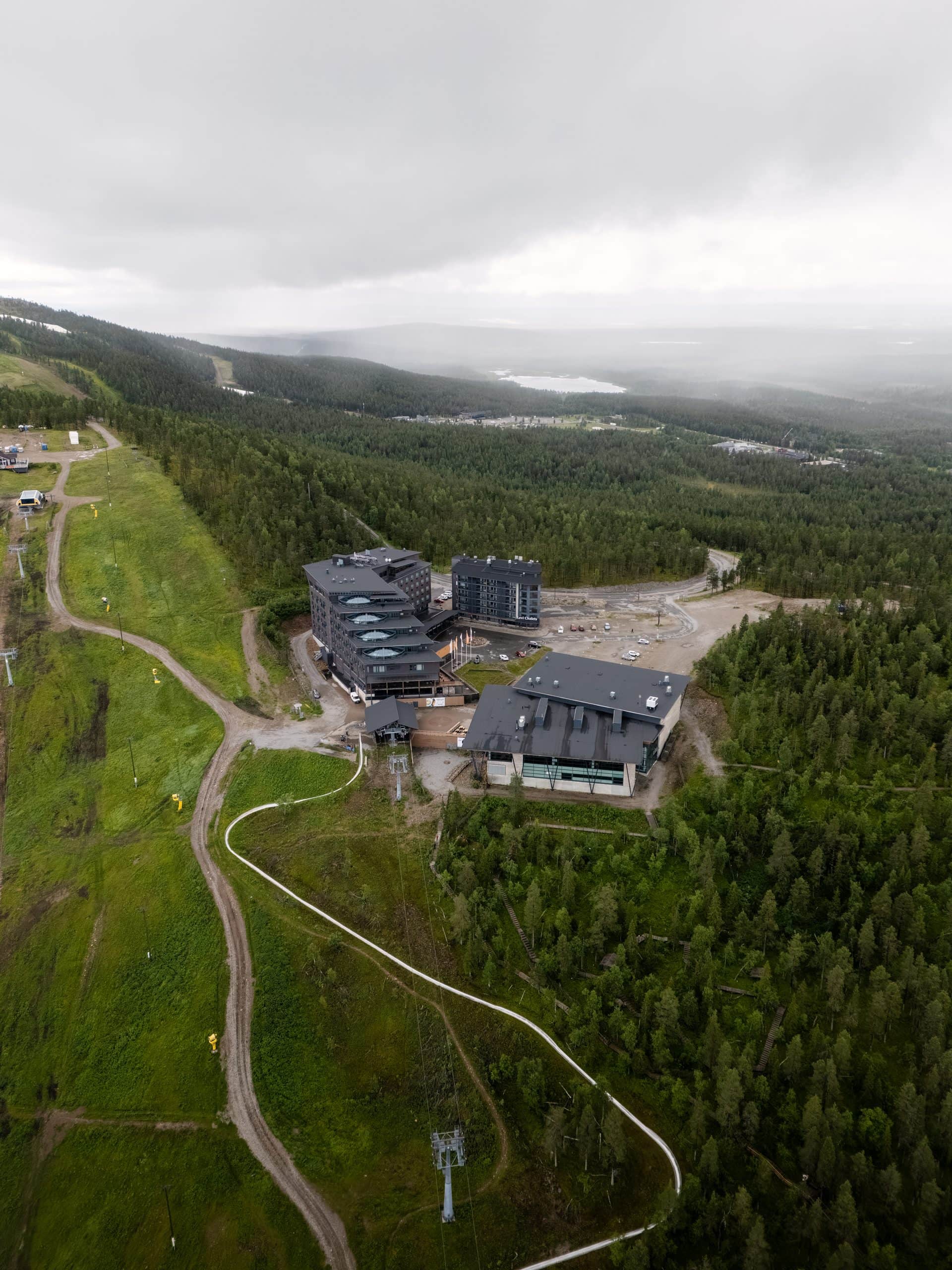 Hotel Levi Panorama ja Levi Summit vehreällä kesärinteellä, matala pilvi laakson päällä