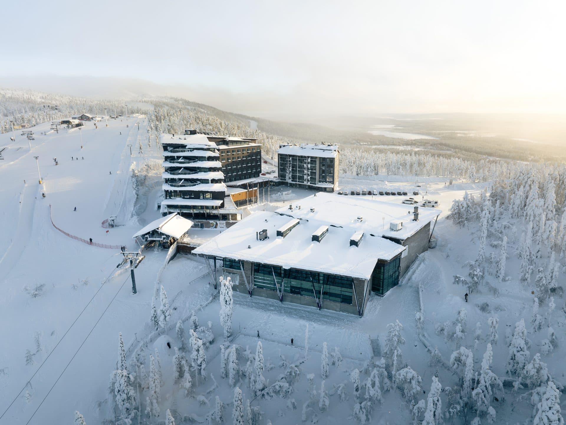Tapahtumakeskus Levi Summit ja Hotel Levi Panorama matalassa talviauringossa, laaksossa sumua