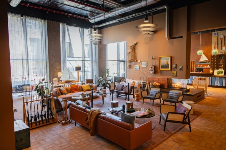 25hours Hotel Copenhagenin oleskelutila, jossa nahkasohvia, takka, purjevenemalleja ja esillä kalastusvapoja