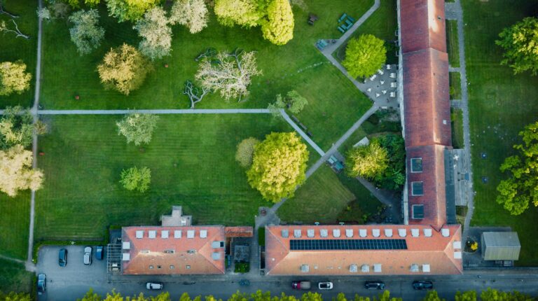 Ilmakuva suoraan ylhäältä Augustenborg Gardenin puiston nurmikoista, poluista ja tiilikattoisista rakennuksista